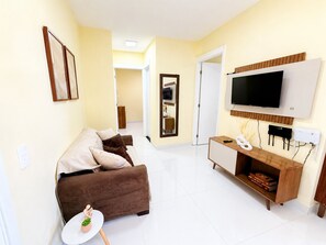 A living room with a sofa, TV, and a small table with a plant.