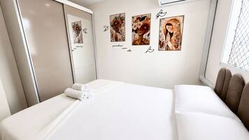 Quarto de hotel com cama, armário, ar condicionado e obras de arte nas paredes.