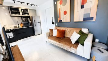 Uma cozinha moderna com forno embutido, geladeira e área de refeições com mesa e cadeiras brancas.