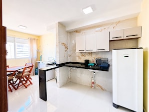 A kitchen with a marble backsplash, a black countertop, and white cabinets.