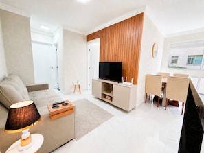 A modern living room with a sofa, TV, and dining area. - Hosts BR - Viva Praia do Futuro (Fortaleza)