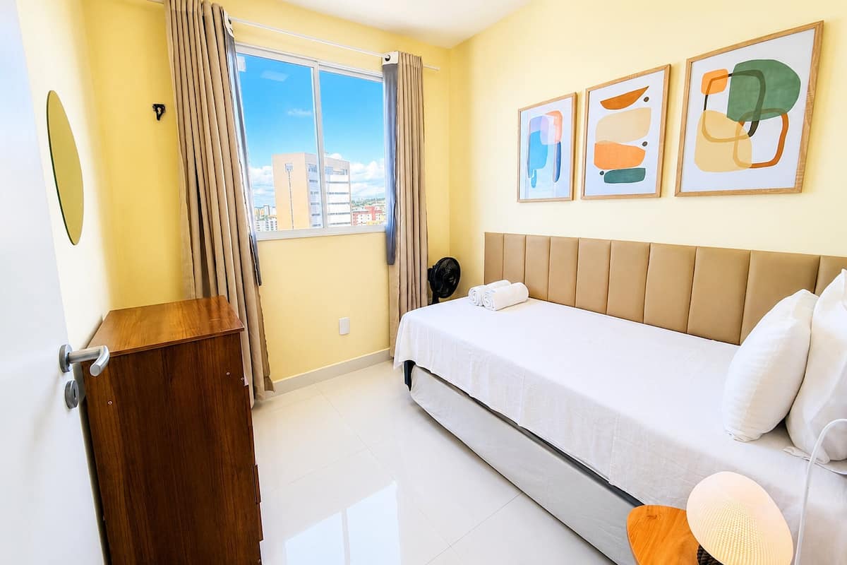 Una habitación de hotel con cama, un escritorio de madera, una ventana con cortinas y decoración en la pared.