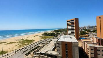 Paisagem costeira urbana com edifícios modernos, uma praia e céu limpo.