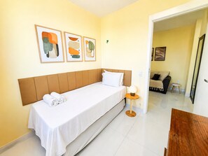 A hotel room with a single bed, a bedside table with a lamp, and abstract art on the wall. - Hosts BR - Viva Praia do Futuro (Fortaleza)