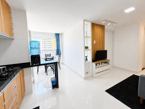 A modern kitchen with a dining area, a flat-screen TV, and a water dispenser. - Hosts BR - Viva Praia do Futuro (Fortaleza)