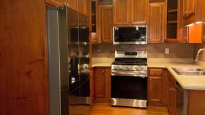 Una cocina con gabinetes de madera, electrodomésticos de acero inoxidable y salpicadero de azulejos.