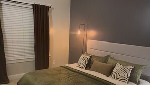 Un dormitorio con una cama, ventilador de techo, mesita de noche y lámpara de pared.