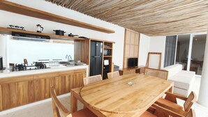 Una cocina moderna con armarios de madera, una isla central y una zona de comedor con mesa y sillas de madera.