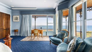 A room with a view of the sea, featuring a blue carpet, a wooden desk, a chair, and a sofa with patterned cushions. - Pelican Clifftop Estate | Magistic views with pool (Mount Eliza)