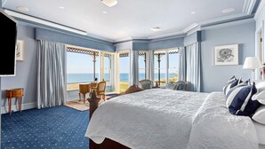 A spacious bedroom with a large bed, a desk, and a view of the sea. - Pelican Clifftop Estate | Magistic views with pool (Mount Eliza)