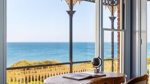 A room with a view of the sea, a wooden desk, and a globe.