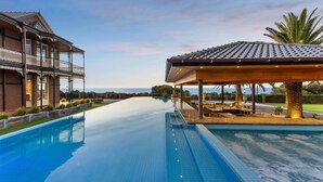 A large swimming pool with a covered area and a building with a balcony. - Pelican Clifftop Estate | Magistic views with pool (Mount Eliza)