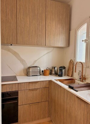 A kitchen with wooden cabinets, a marble countertop, a toaster, a kettle, and a sink with a copper faucet. - Beautiful house for 4 people with WiFi  et  11.50 m mooring (PORT GRIMAUD)