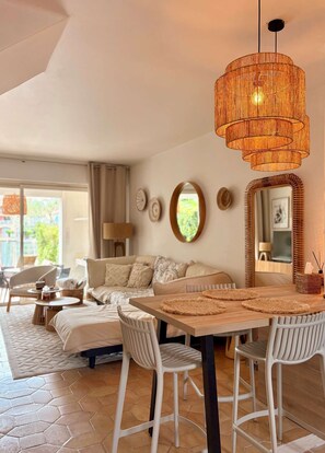 A modern living room with a wooden dining table, white chairs, a large woven pendant light, and a sofa. - Beautiful house for 4 people with WiFi  et  11.50 m mooring (PORT GRIMAUD)