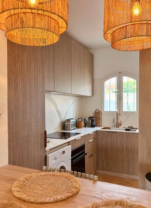 A modern kitchen with wooden cabinetry, a built-in oven, a sink, and a window with a view. - Beautiful house for 4 people with WiFi  et  11.50 m mooring (PORT GRIMAUD)