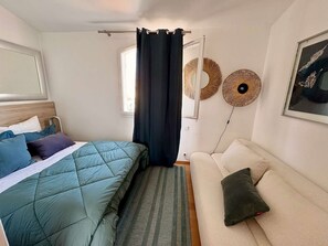 A bedroom with a bed, a sofa, a window with curtains, and wall decorations. - Beautiful house for 4 people with WiFi  et  11.50 m mooring (PORT GRIMAUD)