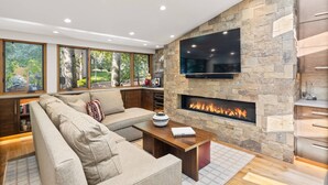 A modern living room with a stone fireplace, a large flat-screen TV, and a comfortable seating area. - Newly Listed! Designer Mountain Retreat Steps from the Gondola. Great Winter Availability! (Aspen)