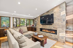 A modern living room with a stone fireplace, a large flat-screen TV, and a comfortable seating area. - Newly Listed! Designer Mountain Retreat Steps from the Gondola. Great Winter Availability! (Aspen)