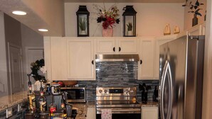 A modern kitchen with white cabinets, stainless steel appliances, a coffee bar, and decorative items on the counter. - Spacious 4-bedroom townhome in tranquil Lakewood with AC (Lakewood)