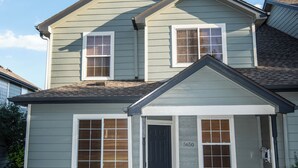 A two-story house with a front porch, a brick foundation, and a number '5650' on the door. - Spacious 4-bedroom townhome in tranquil Lakewood with AC (Lakewood)
