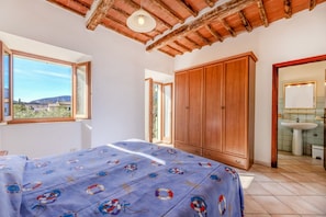 Ein Schlafzimmer mit Bett, Holzschrank und einem Badezimmer mit Waschbecken.