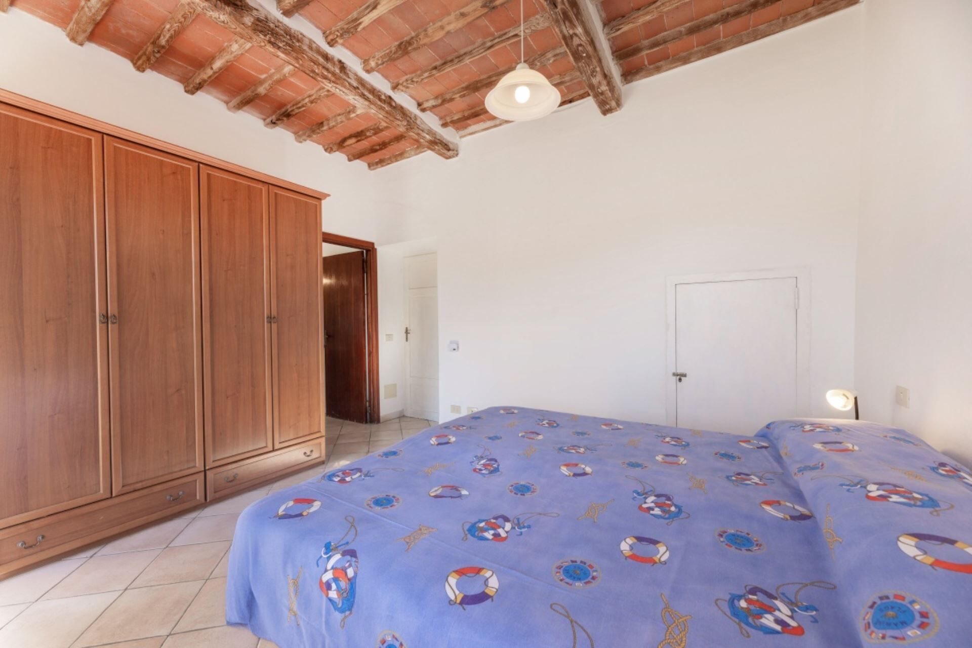 Un dormitorio con una cama grande, un armario de madera y una puerta que da a otra habitación.