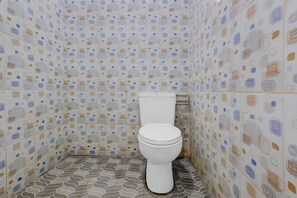 A bathroom with patterned tiles, a toilet, and a tiled floor. - OYO 95140 Metro Guest House (Yogyakarta)