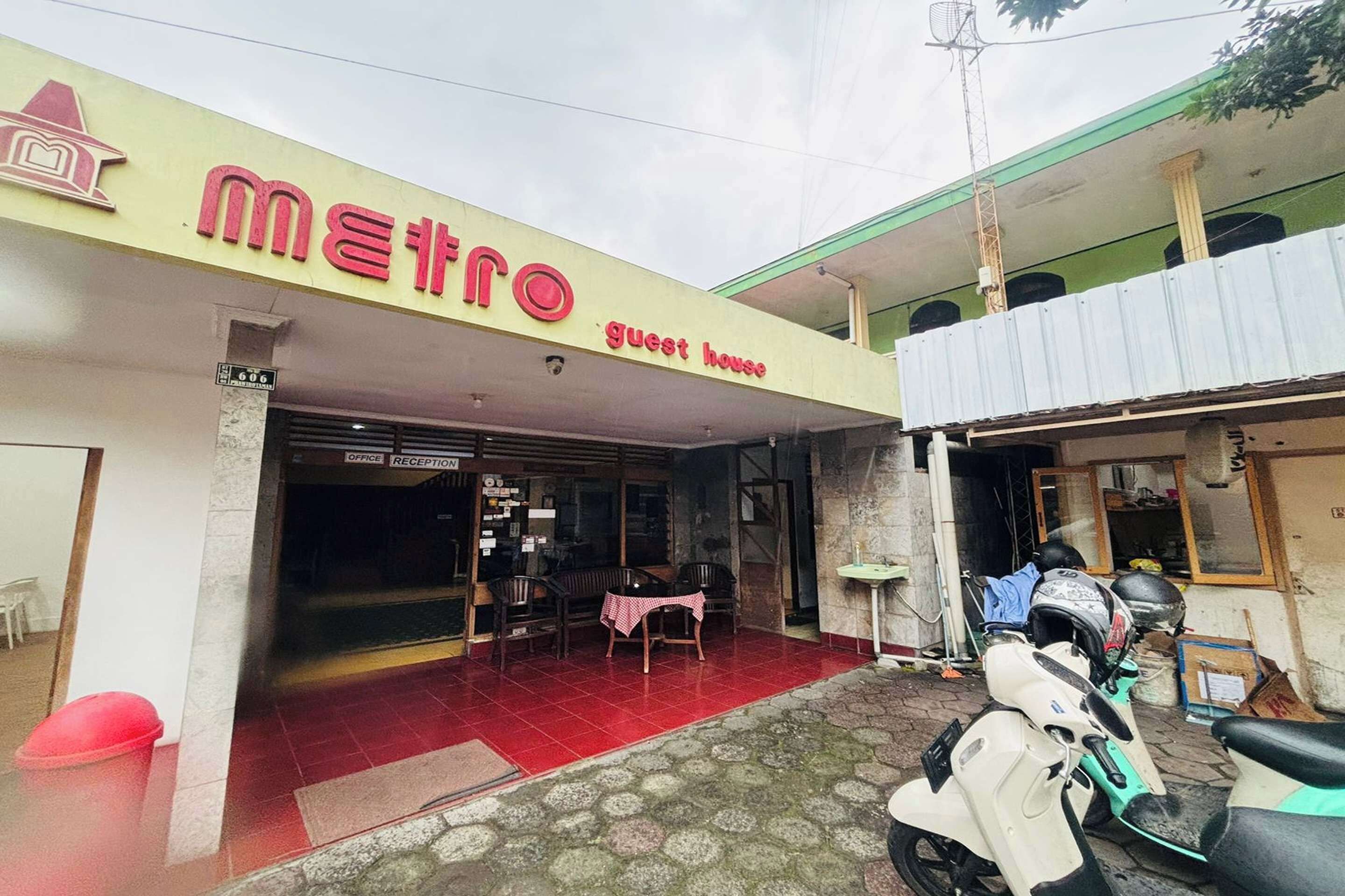 A guest house named Metro with a reception area and a scooter parked outside.