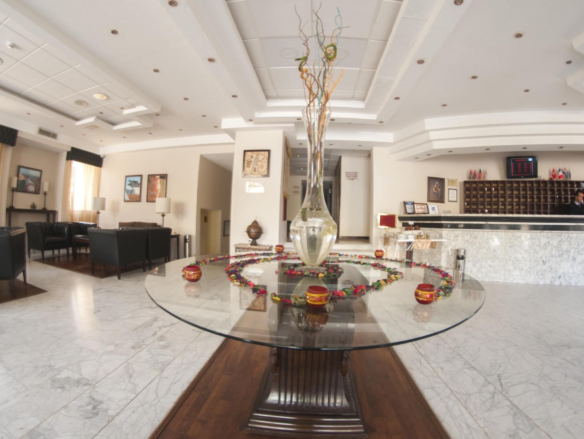 A lobby with a glass-top table, a reception desk, and a seating area with sofas.