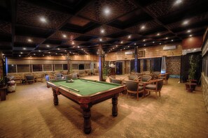 Ein Billardtisch in einem Raum mit Holzwänden und -decke, umgeben von Stühlen.
