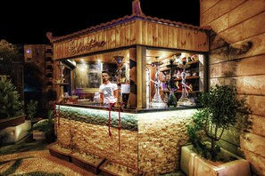 A wooden outdoor bar with a tiled counter, a sign reading 'Stefanis,' and a small plant to the right. - La Maison Hotel (Wadi Musa)
