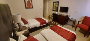 Hotellihuone, jossa on kaksi sänkyä, työpöytä, tuoli, televisio ja työpöytälamppu.