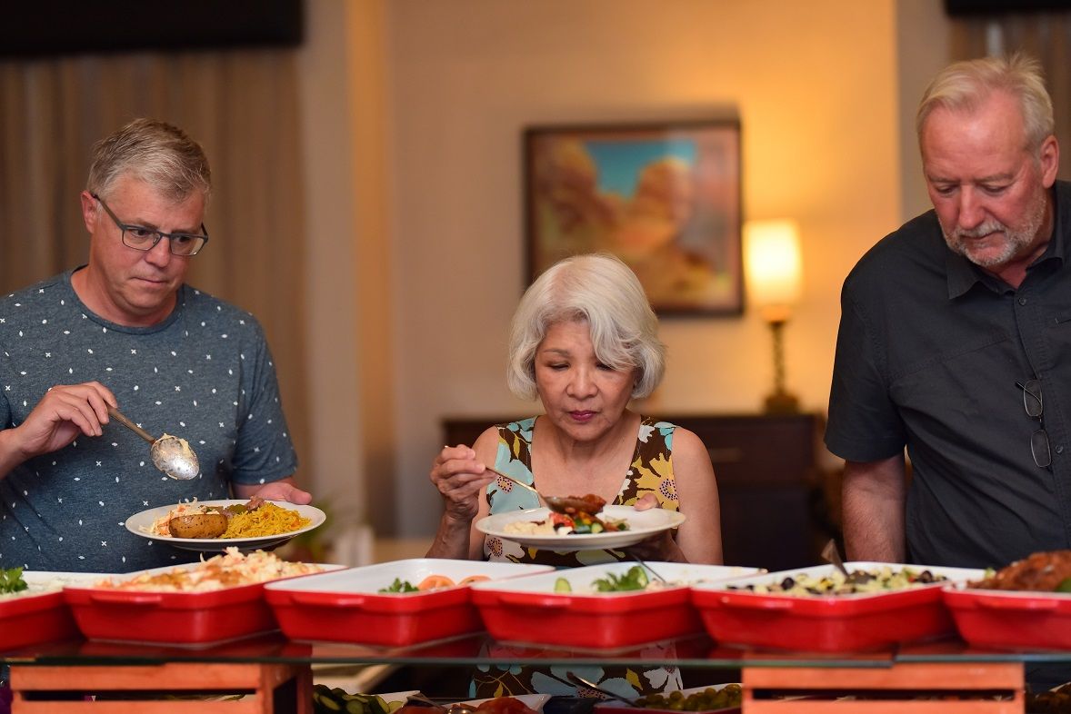 Three people dining at a table with multiple red serving trays.