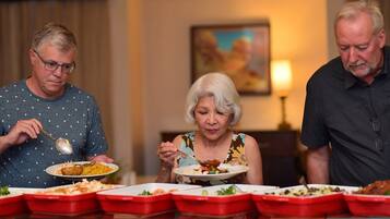 Three people dining at a table with multiple red serving trays.