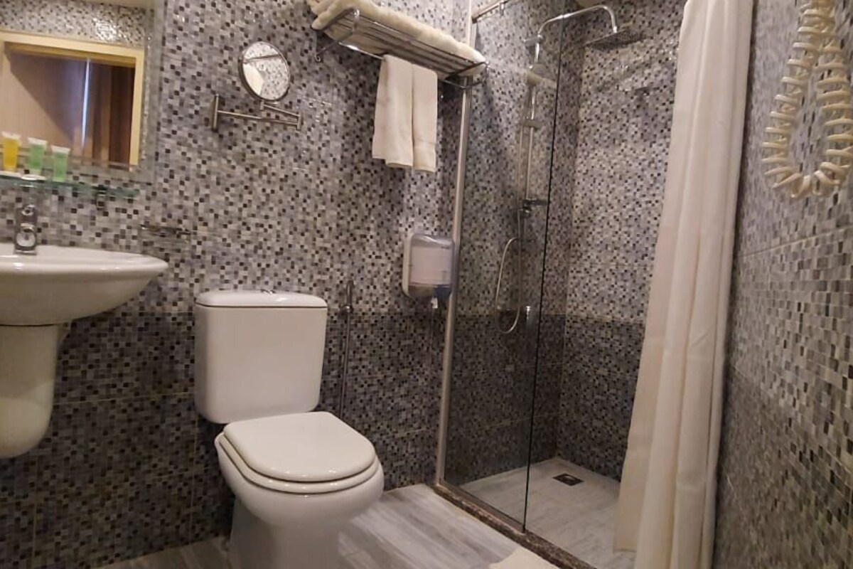 A bathroom with a sink, toilet, and glass-enclosed shower.