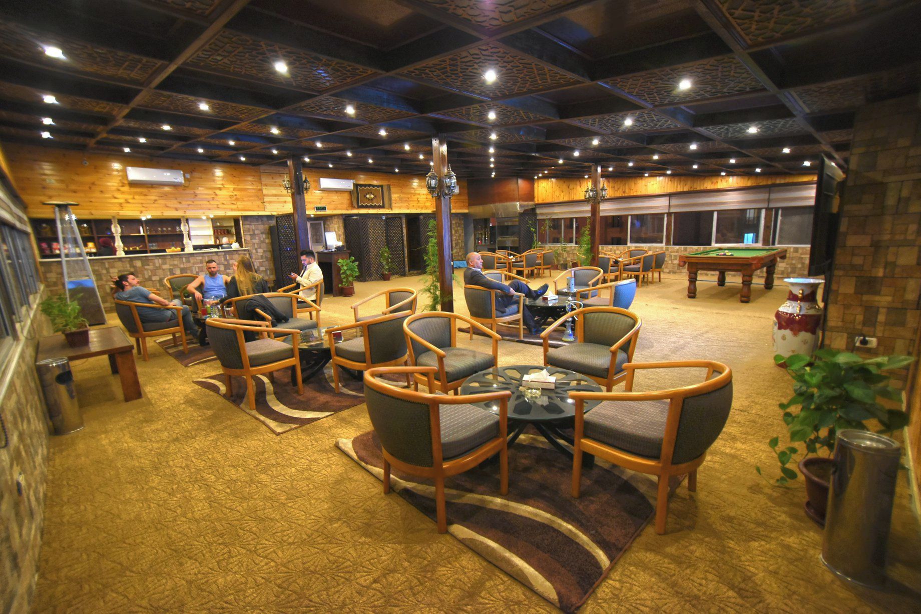A spacious indoor area with multiple seating arrangements, a pool table, and a bar area.