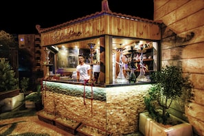 A wooden outdoor bar with a tiled counter, a sign reading 'Stefanis,' and a small plant to the right. - La Maison Hotel (Wadi Musa)