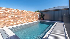 Una piscina con un muro de ladrillo y una cerca metálica.