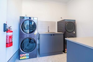 A laundry room with two front-loading washing machines, a sink, and a fire extinguisher.