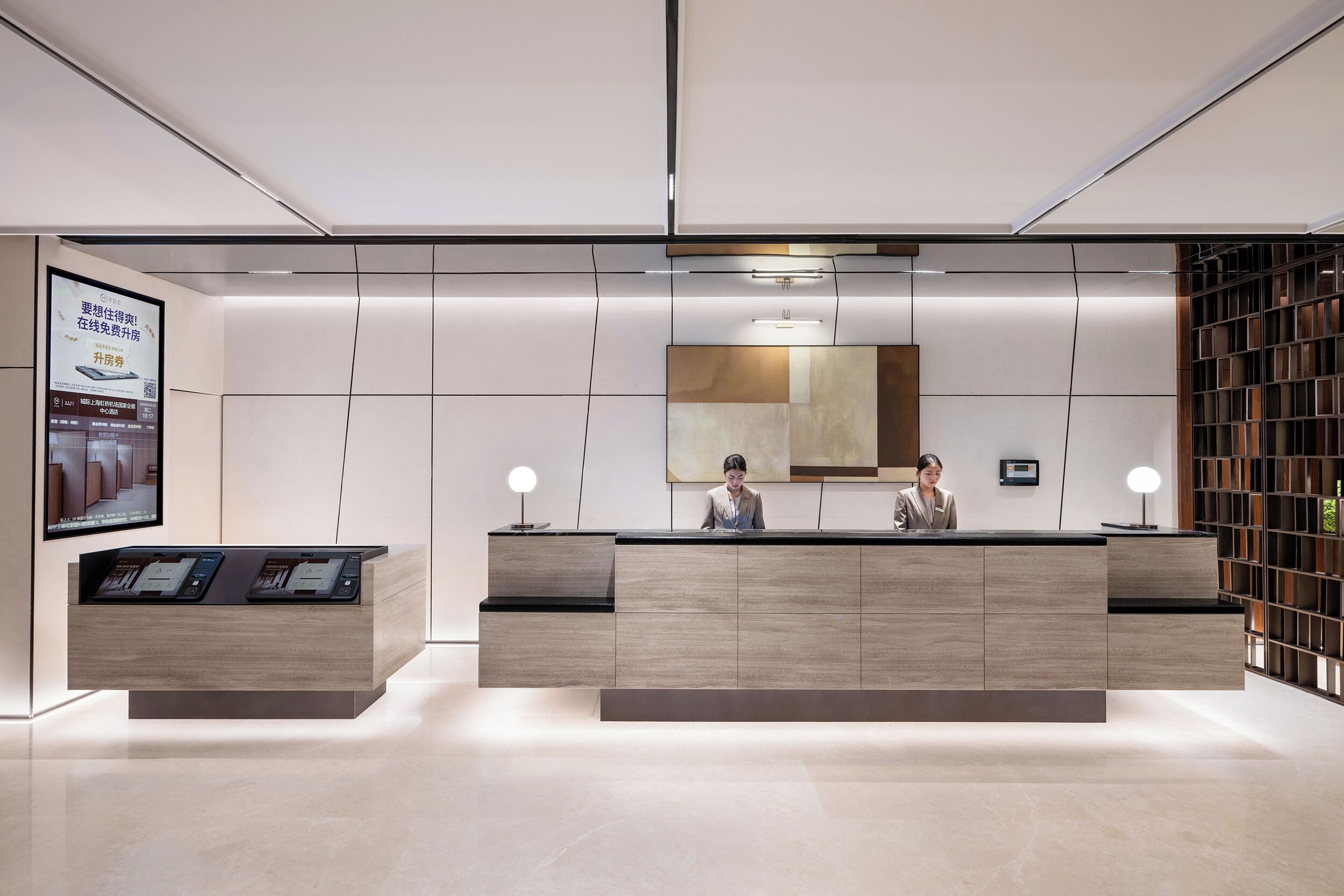 A modern reception desk with a digital display, a large mirror, and a bookshelf.