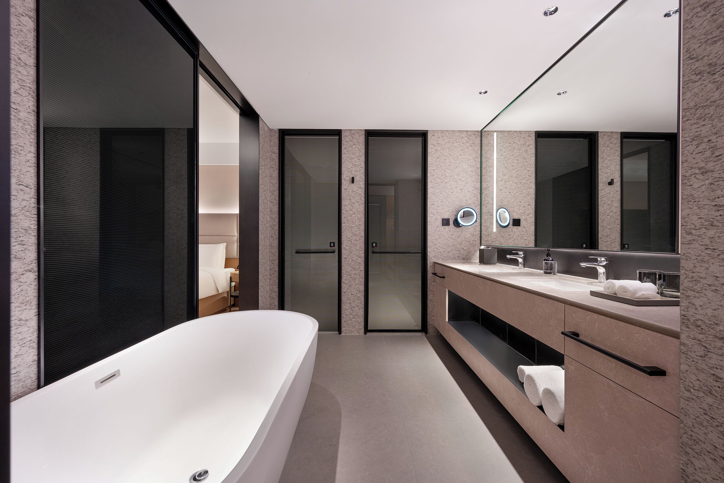 A modern bathroom with a large bathtub, a vanity with a mirror, and a door leading to another room.