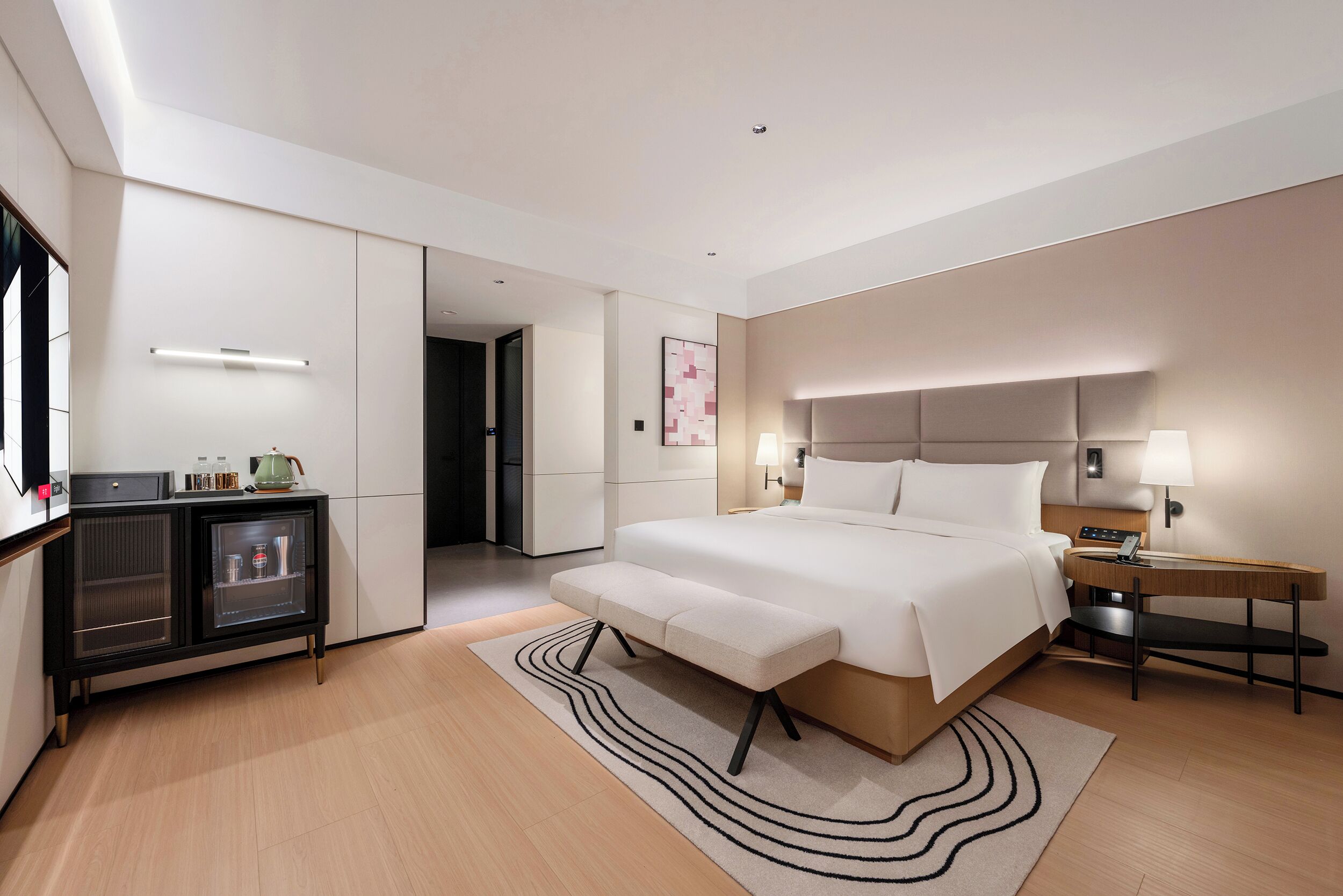Une chambre d’hôtel moderne dotée d’un grand lit, de tables de chevet, d’un bureau et d’un mini-bar.