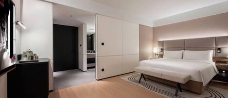 Ein modernes Hotelzimmer mit einem großen Bett, einem Schreibtisch und einem begehbaren Kleiderschrank.