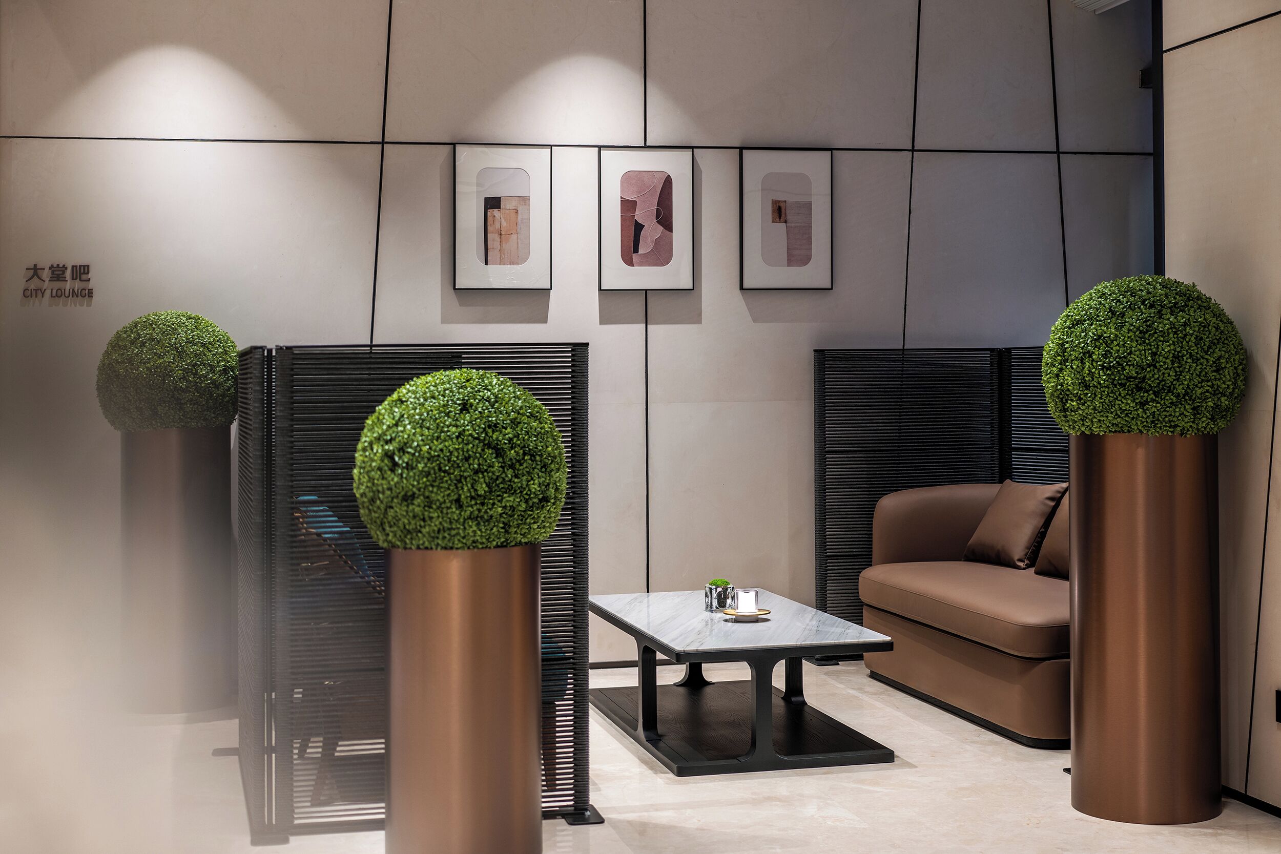 A modern lounge with a sofa, a table, and decorative potted plants.