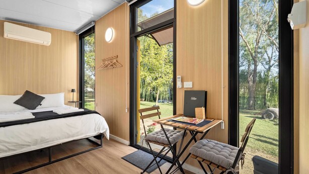 A modern room with a bed, a table, and a view of a garden.