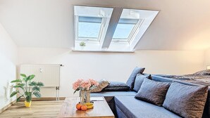 A modern living room with a grey sofa, a wooden coffee table with fruit, a potted plant, and a radiator. - Alpenlodge-Höfats by Interhome (Lechbruck am See)