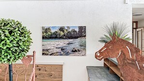 A room with a white wall, a framed landscape painting, a wooden bench, and a potted plant. - Alpenlodge-Höfats by Interhome (Lechbruck am See)