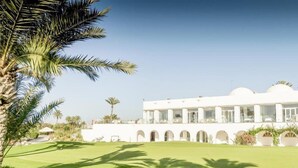 A white building with a symmetrical facade, multiple arches, and a well-maintained lawn. - Robinson Djerba Bahiya (Aghir)