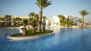 A swimming pool with palm trees and a white building labeled "Wellfit Spa" in the background. - Robinson Djerba Bahiya (Aghir)