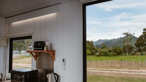 A kitchen with a microwave, kettle, and shelf with jars. - Omoho Stream X by Tiny Away (Kennedy Bay)